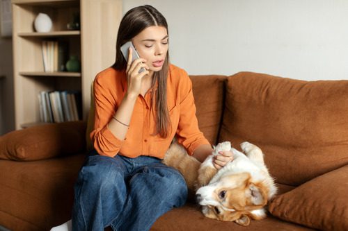 worried-woman-talking-on-the-phone-with-vet-while-watching-her-dog-at-home